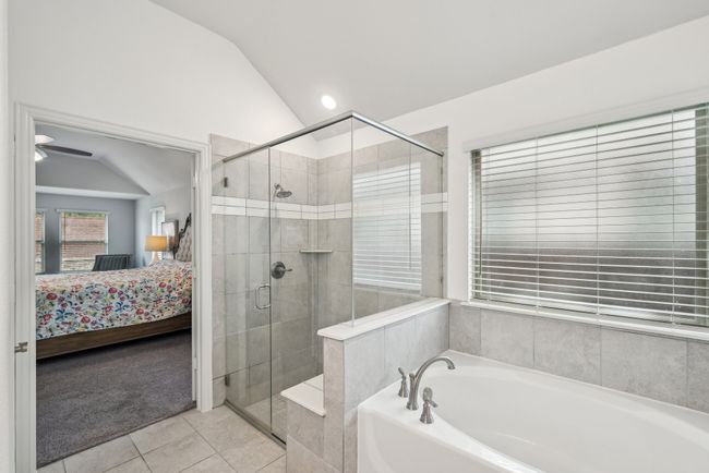 Bathroom featuring connected bathroom, a garden tub, lofted ceiling, a stall shower, and tile patterned floors | Image 26