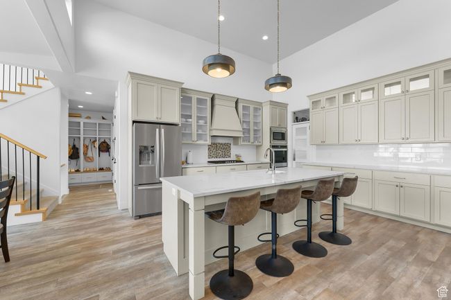 Kitchen with appliances with stainless steel finishes, high vaulted ceiling, custom exhaust hood, an island with sink, and a breakfast bar area | Image 6