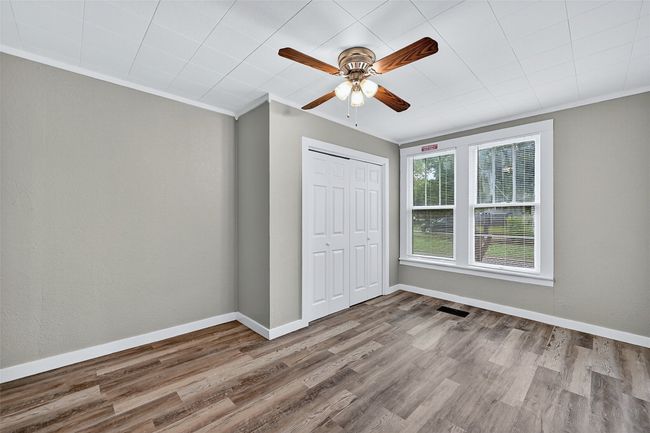 Unfurnished bedroom with ornamental molding, wood finished floors, a closet, and ceiling fan | Image 17