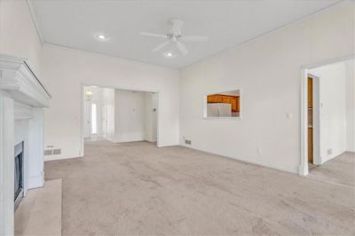 Unfurnished living room featuring light carpet, crown molding, and ceiling fan | Image 3