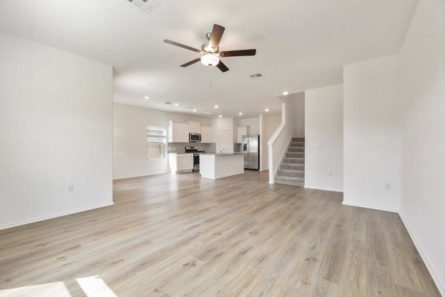 Unfurnished living room with a ceiling fan, stairs, light wood-style flooring, and recessed lighting | Image 17