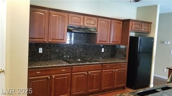Kitchen with freestanding refrigerator, decorative backsplash, dark stone counters, and light wood-type flooring | Image 26