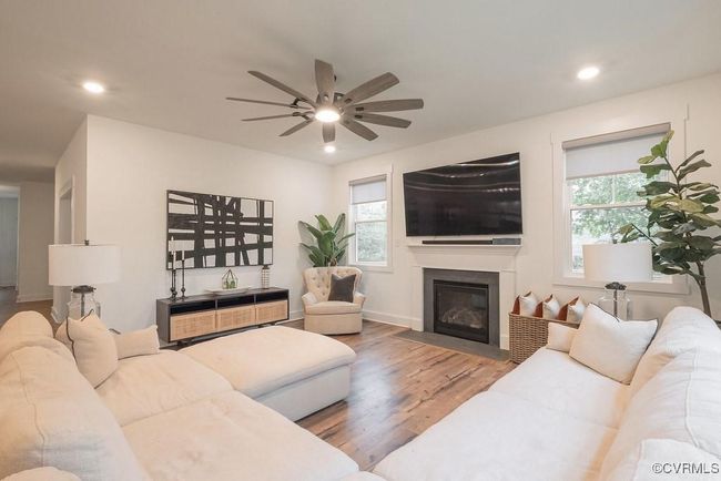Living room with healthy amount of natural light, wood finished floors, ceiling fan, a fireplace with flush hearth, and recessed lighting | Image 23