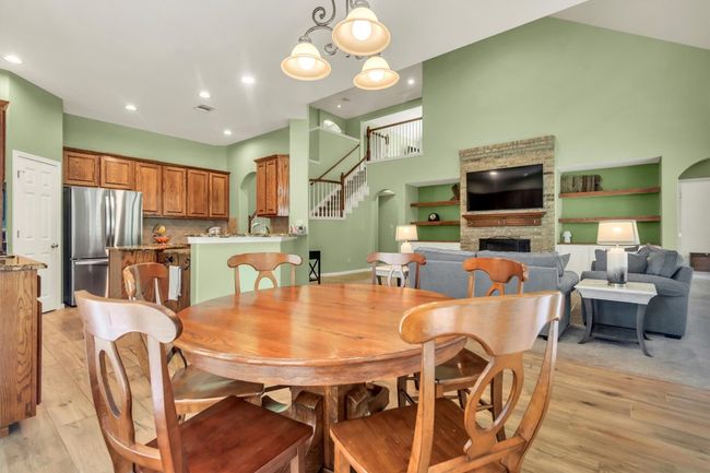 Dining room featuring stairway, baseboards, a stone fireplace, and light wood-type flooring | Image 5