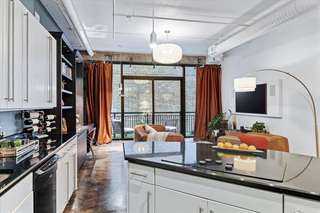 Kitchen featuring black appliances, finished concrete floors, dark countertops, and white cabinetry | Image 6