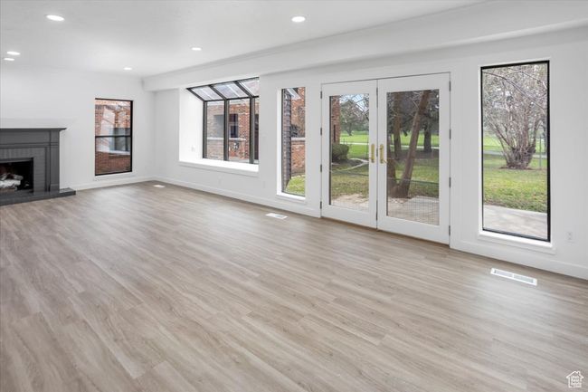 Unfurnished living room with a brick fireplace, light wood-style flooring, baseboards, visible vents, and recessed lighting | Image 6