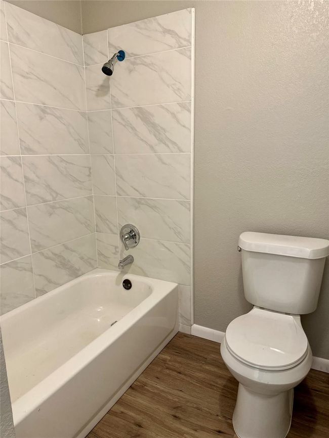 Full bathroom featuring wood finished floors, toilet, baseboards, and shower / tub combination | Image 7