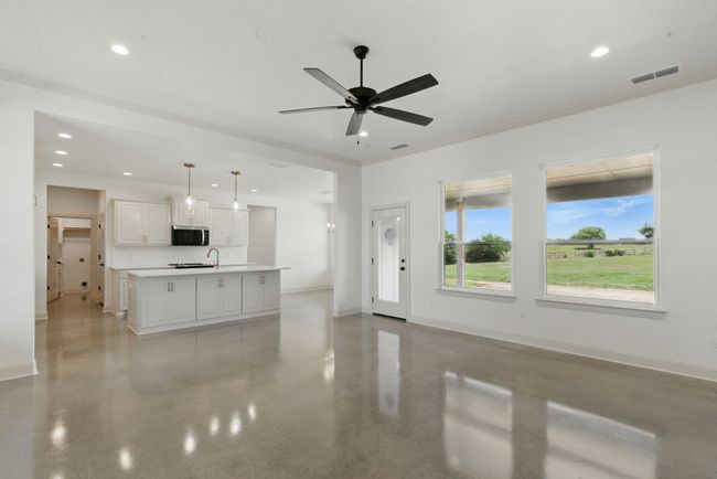 Unfurnished living room with ceiling fan, a sink, baseboards, recessed lighting, and ornamental molding | Image 4