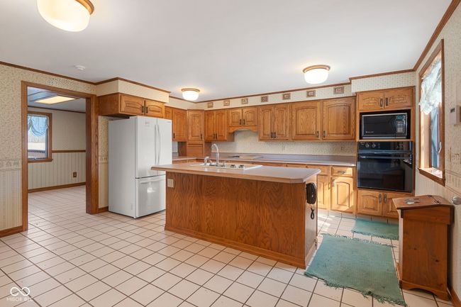 kitchen with black appliances, wallpapered walls, a sink, ornamental molding, and light countertops | Image 12