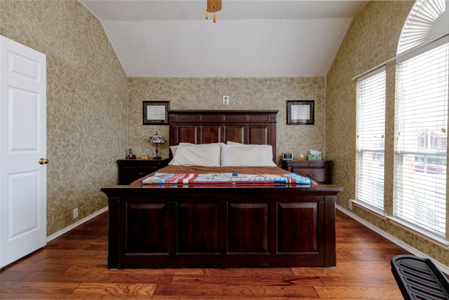 Bedroom with baseboards, wallpapered walls, dark wood-style flooring, and vaulted ceiling | Image 22