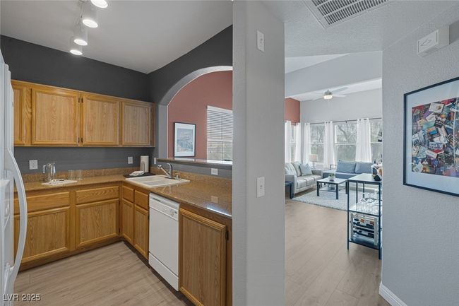 Kitchen with white appliances, arched walkways, a sink, and light wood-style floors | Image 7