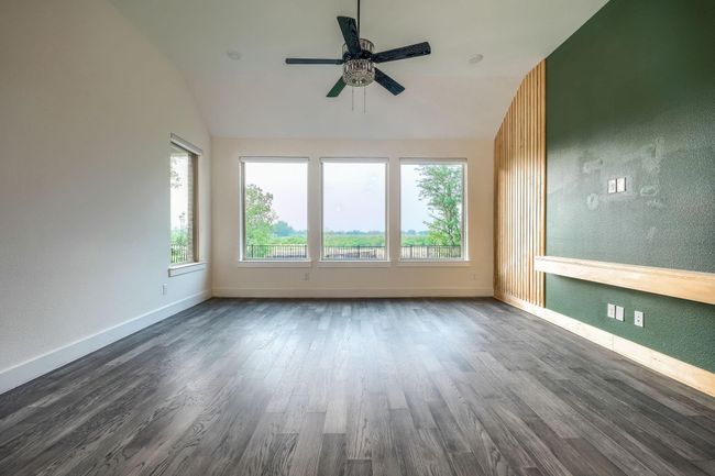 Empty room with vaulted ceiling, dark wood-style flooring, a ceiling fan, baseboards, and a textured wall | Image 15