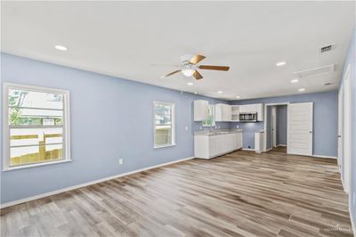 Unfurnished living room featuring light hardwood / wood-style flooring, ceiling fan, and sink | Image 2