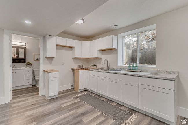 Kitchen with a sink, light wood-type flooring, and white cabinetry | Image 19