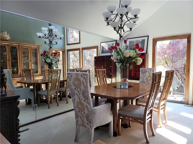 Dining area featuring light carpet, a notable chandelier, and high vaulted ceiling | Image 9