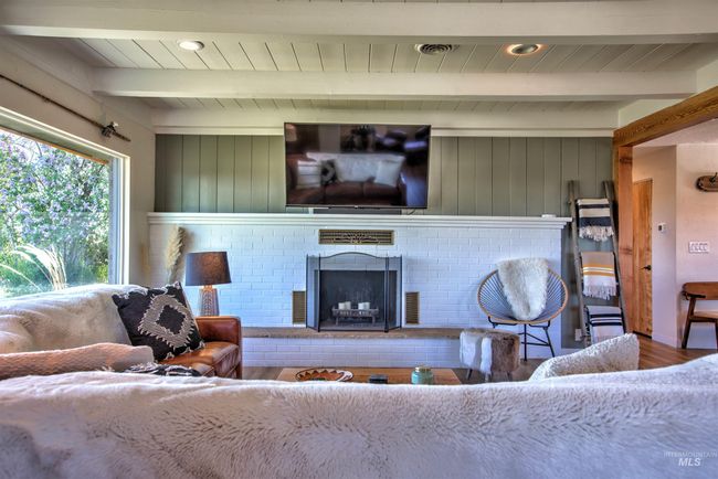 Living area with wood finished floors, a fireplace, and a wooden ceiling with exposed beams | Image 4
