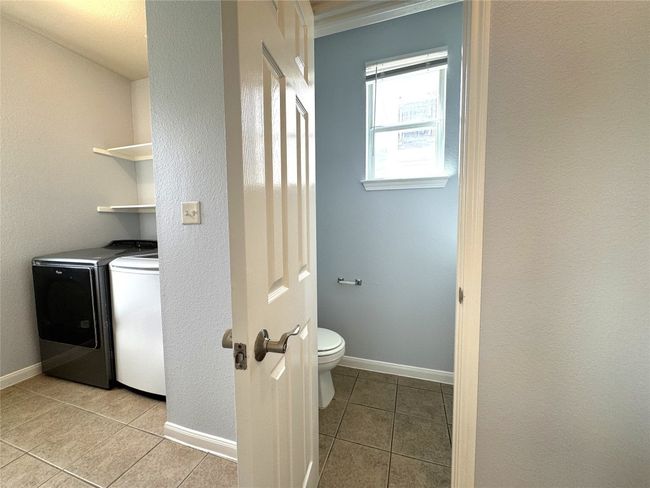 Laundry room featuring washing machine and clothes dryer, light tile patterned flooring, and a textured wall | Image 14