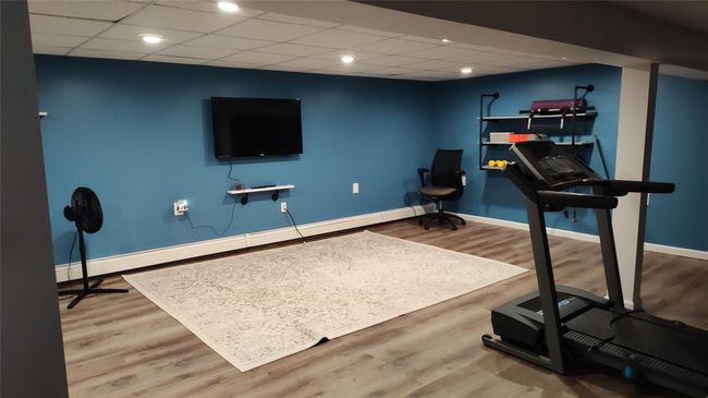 Exercise area with baseboard heating, baseboards, wood finished floors, and a drop ceiling | Image 6