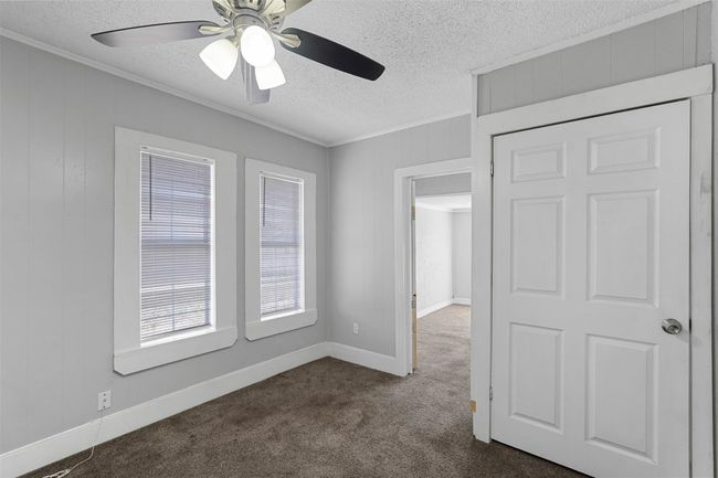 Unfurnished room with crown molding, a textured ceiling, dark colored carpet, and ceiling fan | Image 8