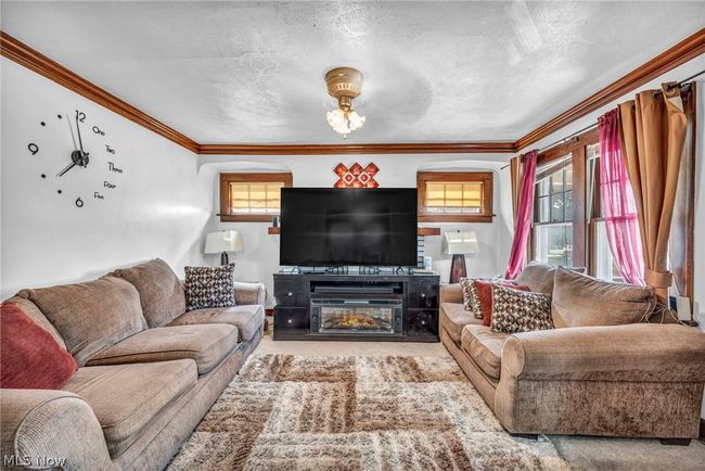 Carpeted living room with a textured ceiling and crown molding | Image 7
