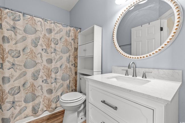 Bathroom with toilet, vanity, a shower with shower curtain, and wood finished floors | Image 20