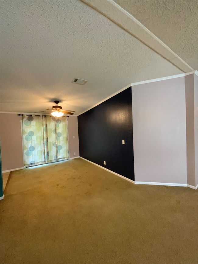 Empty room with carpet, visible vents, a textured ceiling, and ceiling fan | Image 13