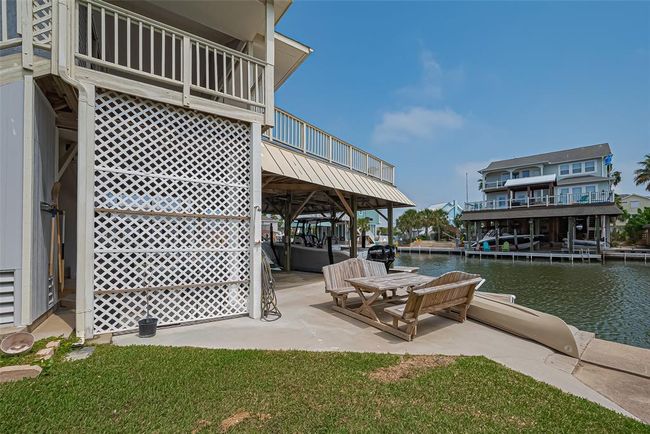 Spacious deck with a boat slip, offering direct canal access. The outdoor seating area is perfect for relaxation, surrounded by a well-maintained lawn and scenic views of neighboring homes. | Image 31