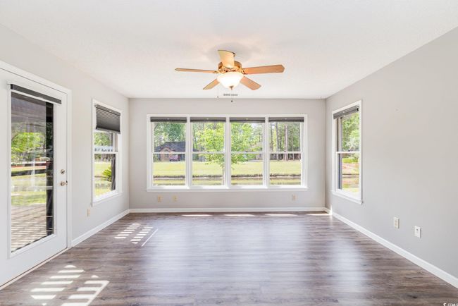 Spare room featuring ceiling fan, baseboards, a healthy amount of sunlight, and dark wood-type flooring | Image 20