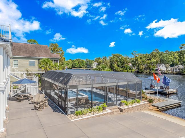 Outdoor pool featuring a water view, a patio, glass enclosure, a dock, and stairway | Image 34