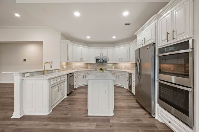 Kitchen featuring light countertops, tasteful backsplash, dark wood-style flooring, stainless steel appliances, and a peninsula | Image 15