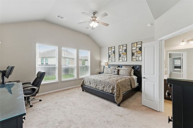 Bedroom with ceiling fan, visible vents, light colored carpet, and lofted ceiling | Image 22