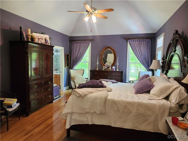 Primary Bedroom featuring vaulted ceiling, a ceiling fan, multiple windows, light wood-style flooring, and high vaulted ceiling | Image 26