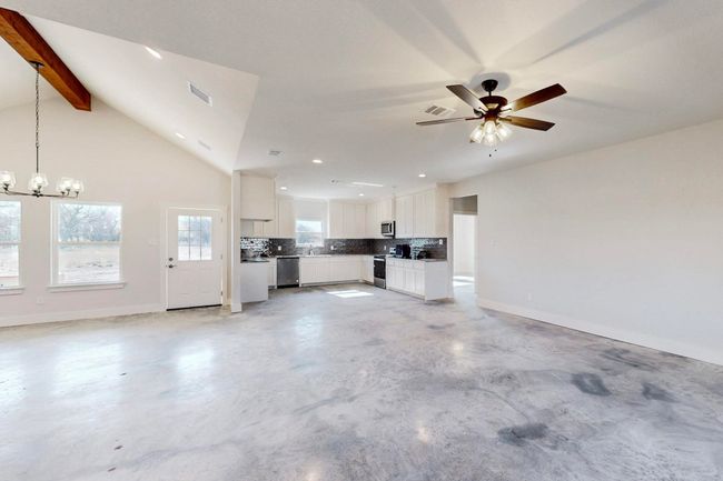 Unfurnished living room with baseboards, recessed lighting, visible vents, ceiling fan with notable chandelier, and concrete flooring | Image 14