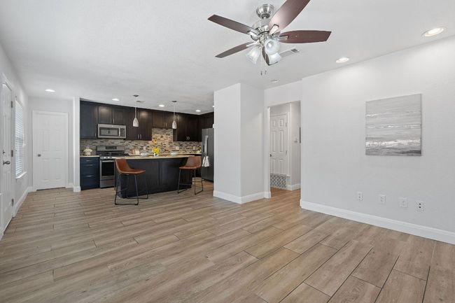Kitchen with appliances with stainless steel finishes, a kitchen breakfast bar, light countertops, recessed lighting, and light wood-type flooring | Image 29