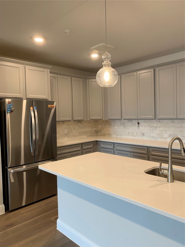 Kitchen with refrigerator, gray cabinets, decorative backsplash, hanging light fixtures, and recessed lighting | Image 6