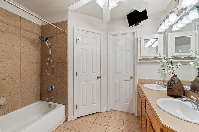 Full bath with tile patterned floors, shower / washtub combination, double vanity, and ceiling fan | Image 27