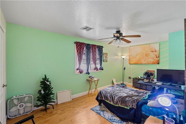 Bedroom with ceiling fan, a textured ceiling, and light hardwood / wood-style flooring | Image 37