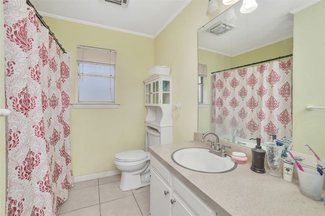 Bathroom with toilet, vanity, tile patterned flooring, crown molding, and curtained shower | Image 26
