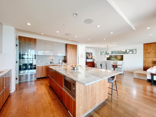 Kitchen featuring modern cabinets, stainless steel microwave, light wood finished floors, recessed lighting, and a sink | Image 13