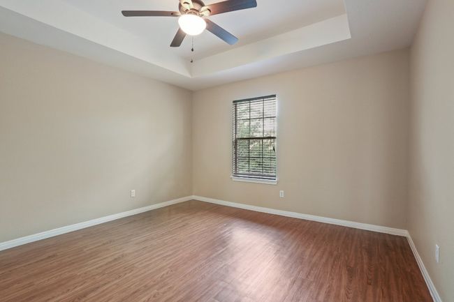 Unfurnished room featuring ceiling fan, baseboards, wood finished floors, and a tray ceiling | Image 27