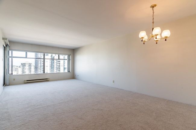 Carpeted spare room with a baseboard heating unit and an inviting chandelier | Image 6