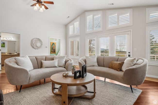 Family room featuring wood finished floors, a healthy amount of sunlight, ceiling fan, and high vaulted ceiling | Image 5