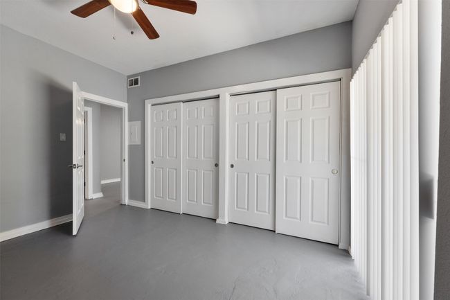 Bedroom featuring baseboards, ceiling fan, finished concrete floors, and two closets | Image 13