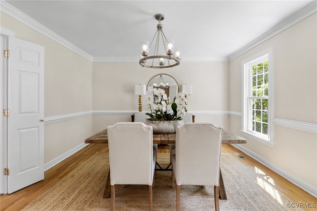 Dining area featuring a chandelier, hardwood floors, ornamental molding and double doors to foyer and kitchen. | Image 11