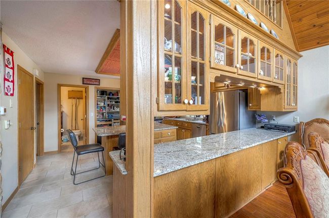 Kitchen featuring stainless steel appliances, glass insert cabinets, brown cabinets, and a peninsula | Image 12