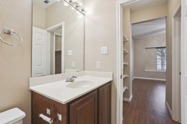 Primary bathroom featuring wood finished floors, toilet, vanity, baseboards, and visible vents | Image 23