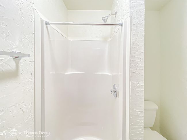 Bathroom featuring a shower stall and a textured wall | Image 23