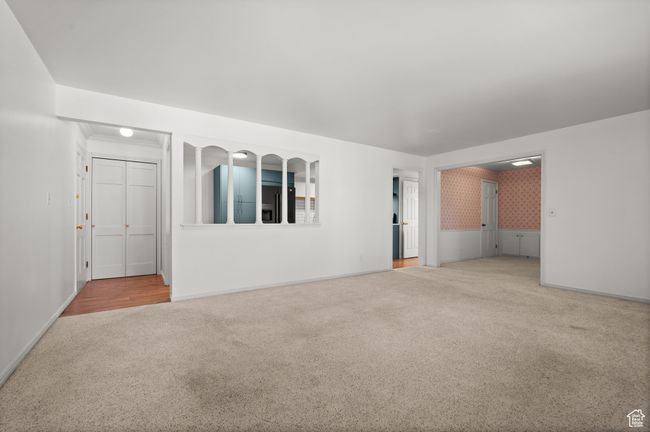 Unfurnished living room featuring carpet flooring, baseboards, and a wainscoted wall | Image 11