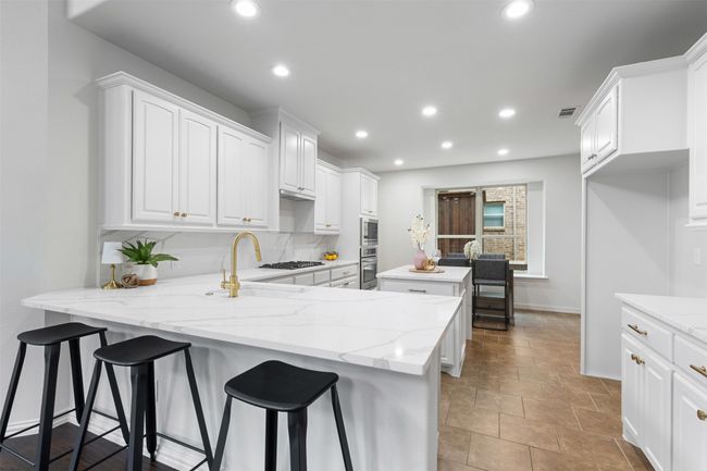 Kitchen featuring oven, white cabinetry, a kitchen island, and a sink | Image 8
