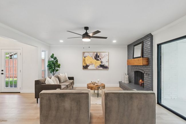 Living area with light wood-type flooring, a brick fireplace, ornamental molding, a ceiling fan, and recessed lighting | Image 12
